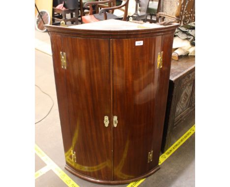 A 19th Century mahogany bow fronted hanging corner cupboard,&nbsp;interior shelves enclosed by a pair of doors hung to brass 