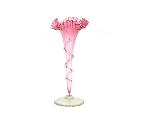 A cranberry glass trumpet shaped posy vase,&nbsp;with frilled rim and clear glass trailing foliage, raised on a clear glass s