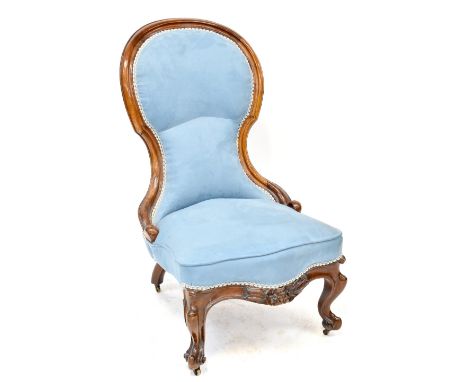 A Victorian walnut spoon back nursing chair, upholstered in a light blue velure, with carved floral motifs, on squat cabriole