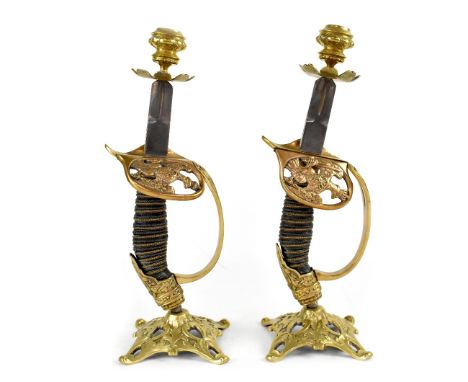A pair of candlesticks fashioned from WWI era German Imperial Army cavalry sword handles, decorated brass cast bases and cand