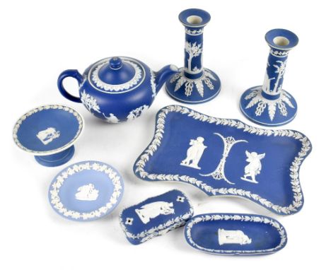 A collection of dark blue Wedgwood jasperware comprising teapot, pair of candlesticks, a tray, lozenge-shaped trinket dish, a