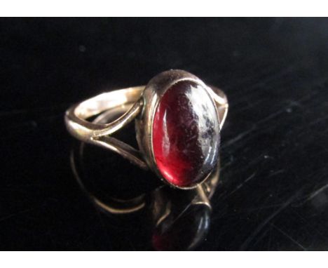A rose gold ring set with an oval cabochon garnet in open shoulders, unmarked. Size K, 2.7g 