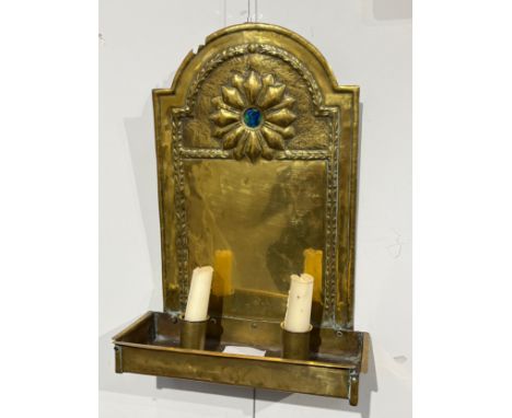 An Arts and Crafts wall hanging double candle sconce with brass arched back plate with hammered decoration and flower motif w