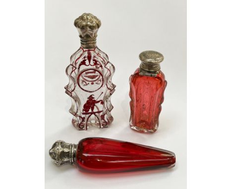 Three various scent bottles, one enriched with gilt, one ruby glass and of tapering form, one with red line detail and figura