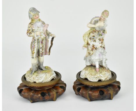 A pair of 19th century German porcelain figures, modelled as a lady and gentleman, both well groomed with lace trimmed clothi