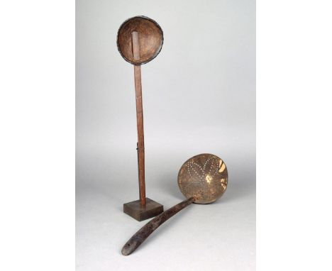 A Ceylon coconut shell and palmwood spoon with a hand written label, 40.5cm long, on a stand, and a similar ladle with a pier