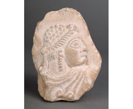 A Sumerian fragment limestone, relief carved a figural bust, with a beaded and braided coiffure and wearing a cloak, 12cm hig