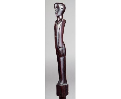A Solomon Islands staff Melanesia wood, carved with a standing male figure wearing a jacket with his arms by his sides, with 