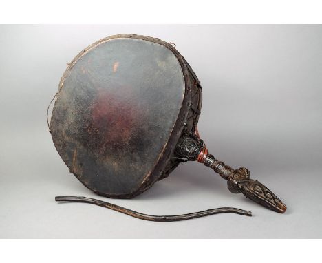 A Nepalese Shaman's drum carved wood, vellum and fibre with a curved stick beater, 60cm long. (2)