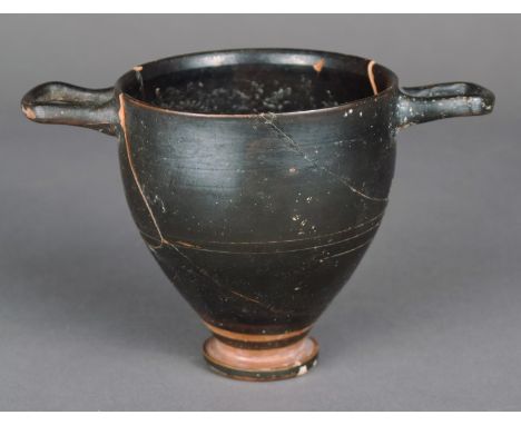A black glazed skyphos Greek raised on a circular foot with incised line decoration and a pair of open handles, 9cm high.