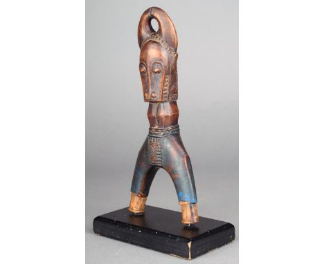 A Baule catapult Ivory Coast wood, with buffalo head finial, traces of blue paint, 17cm high, on a stand. (2) Provenance Moni