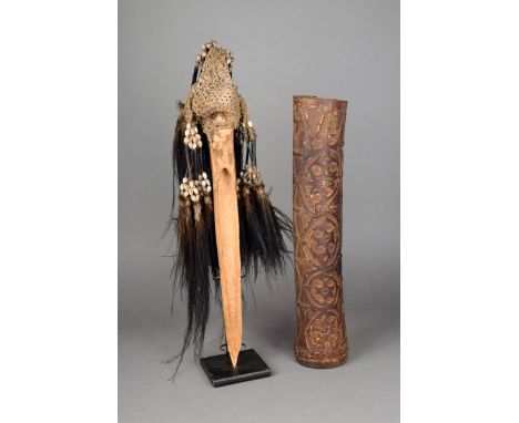 An Asmat dagger Irian Jaya, Melanesia Cassowary bone, with woven fibre, seeds and feathers, 38cm long, and an Asmat carved ba