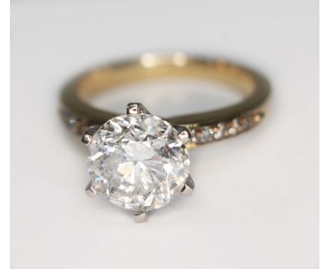 A diamond solitaire ring, the six claw set round brilliant cut diamond weighing approx. 2.53ct, diamond set shoulders, yellow