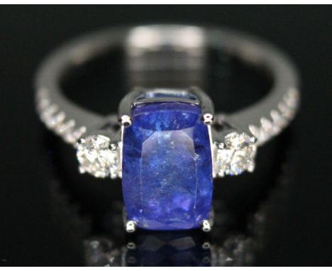 A tanzanite and diamond cluster ring, the central rectangular cushion cut stone weighing approx. 3.21 carats, mounted above t