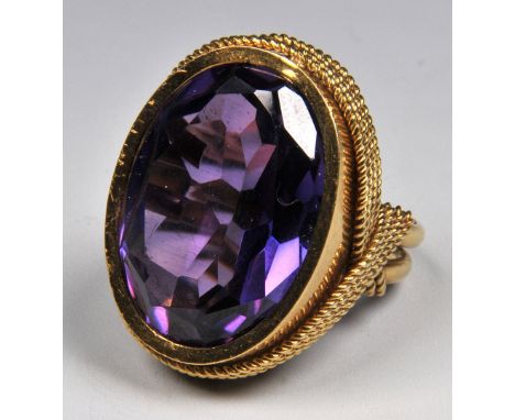 AN OUTSIZED COSTUME RING with rope-twist decoration and set with oval amethyst