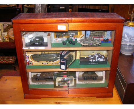 A table top display case containing die cast model Army vehicles, including Corgi and Solido 