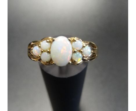 OPAL CLUSTER RINGthe central oval cabochon opal flanked by three round cabochon opals to each side, on nine carat gold shank,