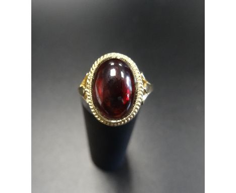 GARNET DRESS RINGthe large oval cabochon garnet in rope twist effect mount, on nine carat gold shank, ring size N-O 