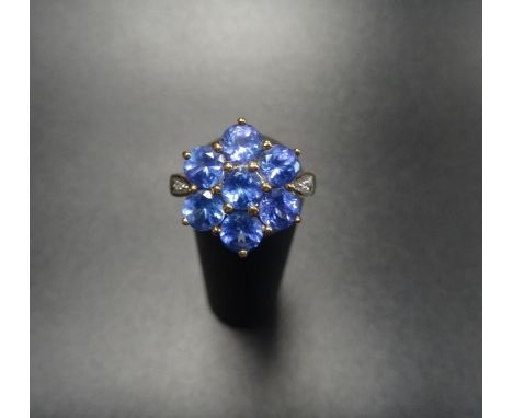 TANZANITE CLUSTER DRESS RINGthe seven stone tanzanite cluster flanked by a small diamond to each shoulder, on nine carat gold