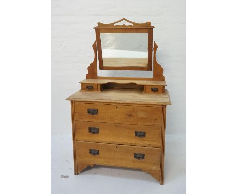EDWARDIAN LIGHT OAK DRESSING CHESTwith a shaped adjustable bevelled mirror back above two jewellery drawers, with three long 