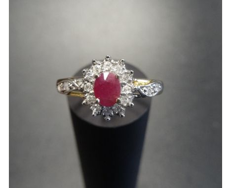 RUBY AND DIAMOND CLUSTER RINGthe central oval cut ruby in twelve diamond surround and with further small diamonds to the shou