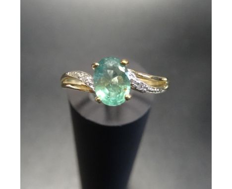 EMERALD AND DIAMOND RINGthe central oval cut emerald flanked by twist design split shoulders with textured detail and a small