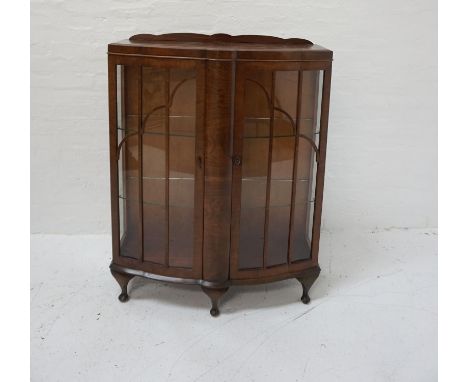 1950s WALNUT BOW FRONT DISPLAY CABINETwith a shaped raised back above a pair of glazed doors and side panels, standing on sto