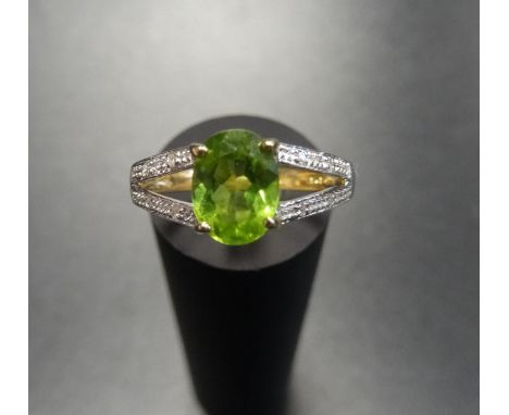 PERIDOT AND DIAMOND RINGthe central oval cut peridot flanked by diamond set split shoulders, on nine carat gold shank, ring s