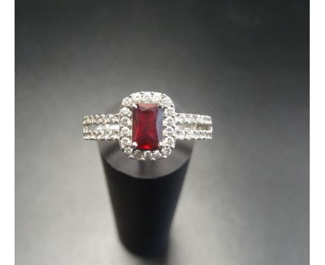 RUBY AND CZ DRESS RINGthe radiant cut ruby in CZ surround and with further CZ to the split shoulders, on nine carat white gol