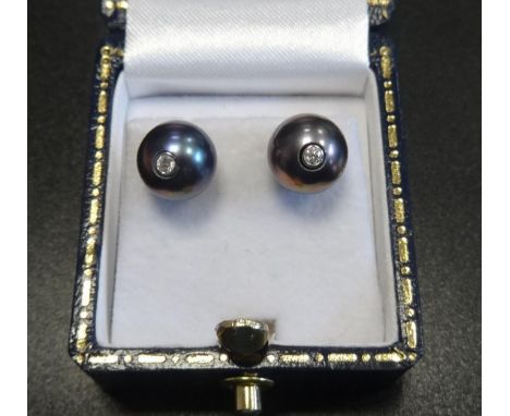 UNUSUAL PAIR OF BLACK PEARL AND DIAMOND STUD EARRINGSthe diamond set posts to the centre of each pearl, in eighteen carat whi