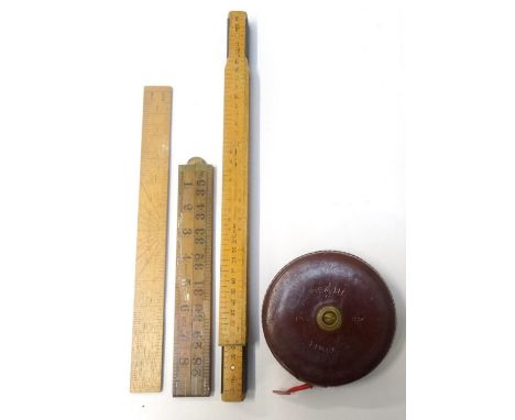 METALLIC TREBLE SURVEYORS TAPEin a circular leather case with brass fittings and a cloth tape, a folding four section measure