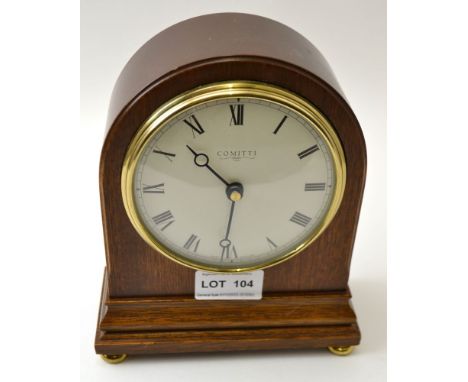 A "Comitti" mahogany cased mantel clock raised on brass bun feet, circular dial with Roman numerals, 19cm high