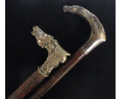 A riding crop and a walking stick with white metal horse head handles, one bearing European marks  