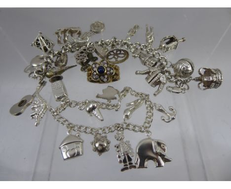 A Lady's Sterling Silver Charm Bracelet, with approx seventeen silver charms on heart shaped clasp approx 92 gms, with anothe