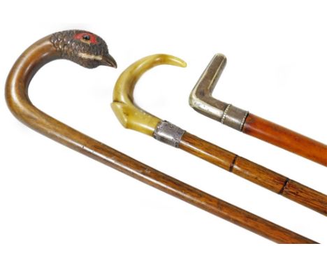 An early 20thC walking cane, with carved pheasant end, 50cm W, a horn handle walking cane with silver collar and another walk
