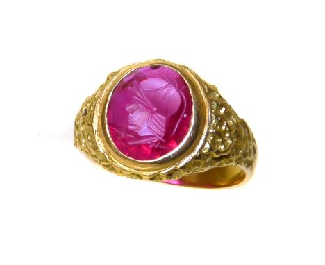 A synthetic ruby intaglio ring, the oval synthetic ruby intaglio within a textures ring mount, stamped 18ct, ring size S, gro