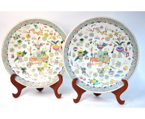 A pair of polychrome enamel dishes, decorated in the famille rose style with Chinese Scholar's implements; 39cm diameter; 19t