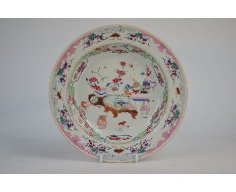 A famille rose shallow soup dish, decorated with floral arrangements in a Scholar's interior, 22.5cm diameter, Yongzheng/Qian