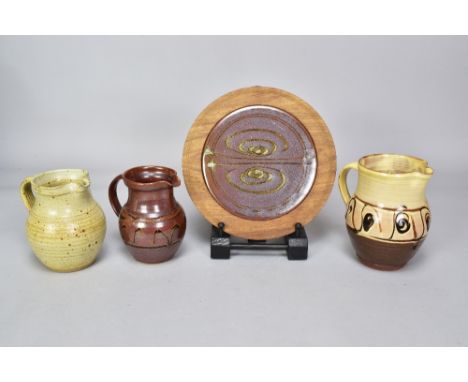 Winchcombe Pottery; a slipware jug and two stoneware jugs, impressed pottery marks, tallest 16cm, and a stoneware hot plate/s
