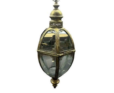 Modern bronze finish glazed lantern of hexagonal tapering form, raised upon bronze finish stand and four scroll supports, H16