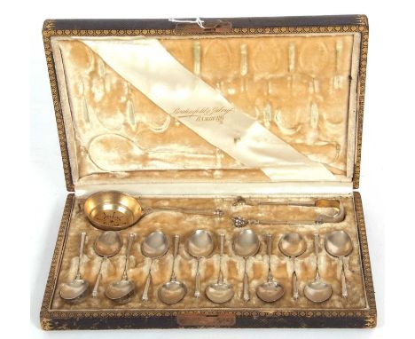 Cased set of twelve German silver coffee spoons with scale engraved decorative handles together with matching tea strainer an