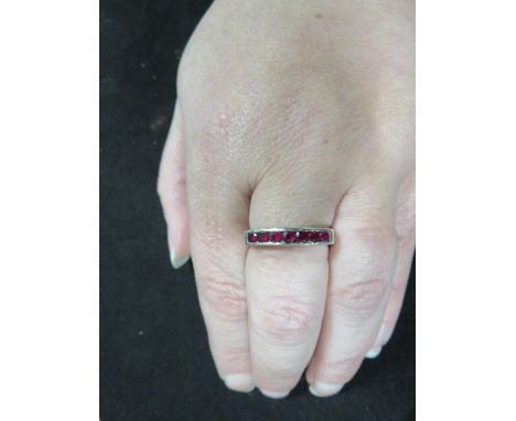 A hallmarked 9 carat white gold half eternity style channel set ruby ring approx weight 3.8g ring size N 1/2 