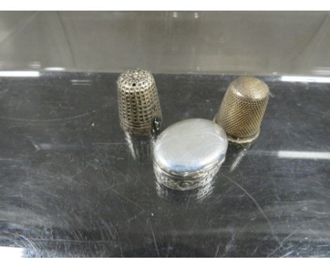 A vintage silver pill box and two silver thimbles 