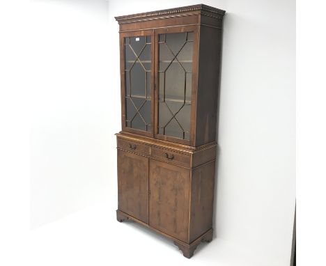 Georgian style yew wood bookcase on cupboard, two doors enclosing two shelves above two drawers and two cupboards on shaped b