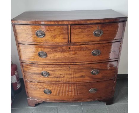 A 19th century flame mahogany bow fronted chest of two short over three long drawers, having oval drop brass handles and brac