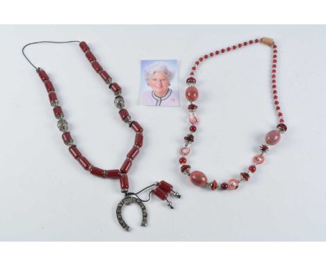 A string of Middle Eastern simulated cherry amber and white metal beads, together with a costume necklace with ceramic and mo