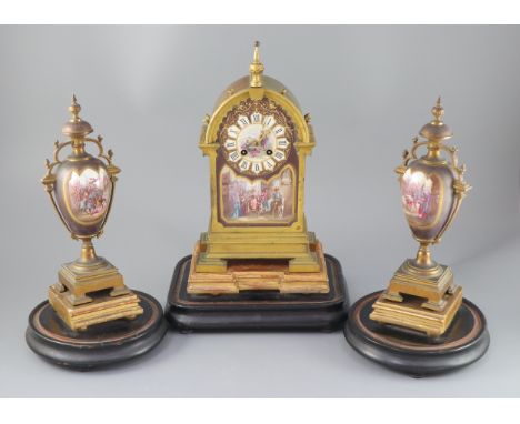 A 19th century French ormolu and enamelled porcelain clock garniture, the eight day clock with arched architectural case flan