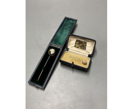 A cased early 20th century yellow metal and carved sardonyx set stick pin, 8cm and a similar 'shell' stick pin, 56mm.