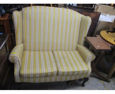 An upholstered two seater sofa with alternating floral and yellow striped upholstery, on cabriole legs 