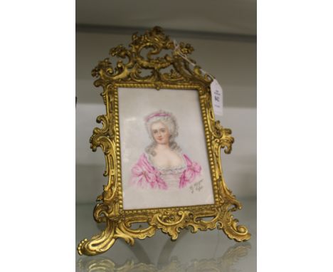 G Goger, head and shoulders portrait of a young lady on porcelain, in a decorative ormolu easel frame.